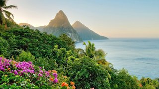 Blick auf die grüne Küste von St. Lucia mit einem Sonnenaufgang hinter den Bergen